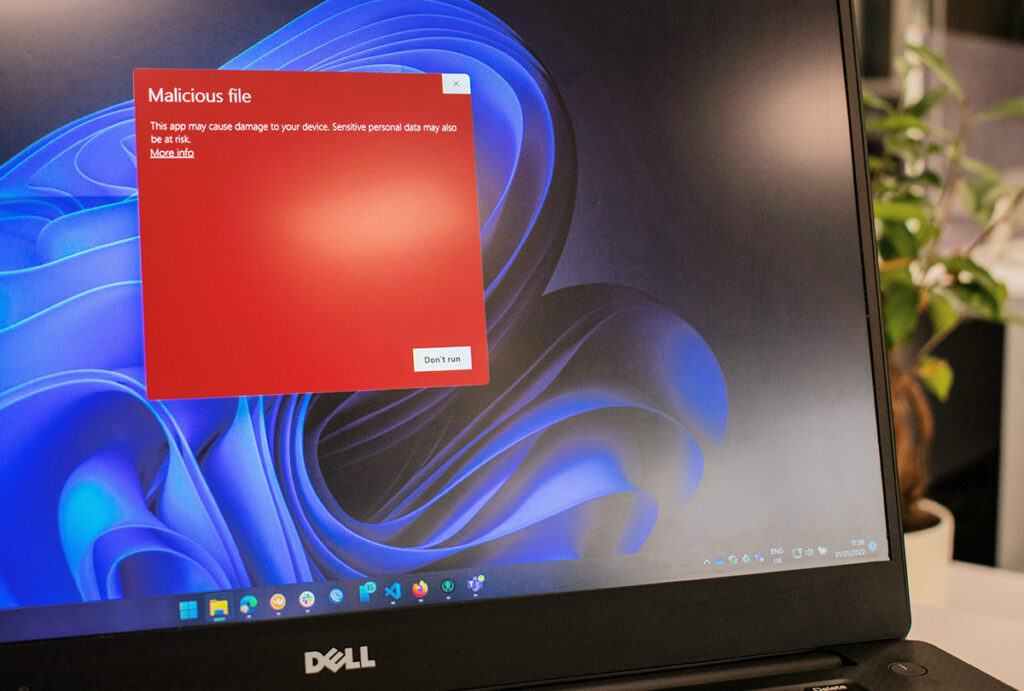 Laptop zeigt Warnmeldung 'Malicious file' mit Hinweis auf Gefahr für persönliche Daten und Option 'Don't run', Thema Cyberversicherung